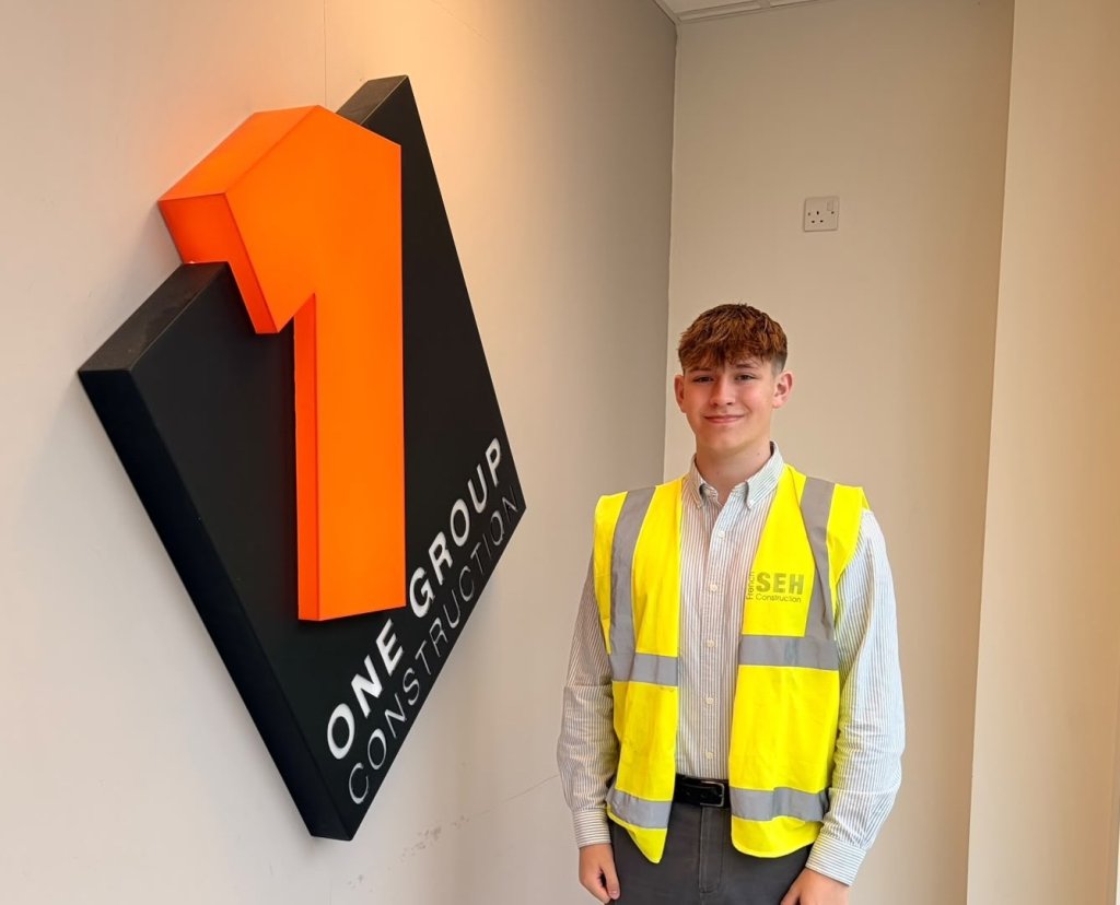 Elijah Trigg, SEH French work placement student standing by One Group logo